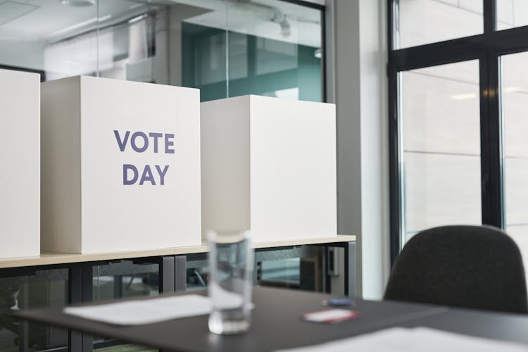 Big Boxes With A Sign Vote Day Standing On Table In An Office 