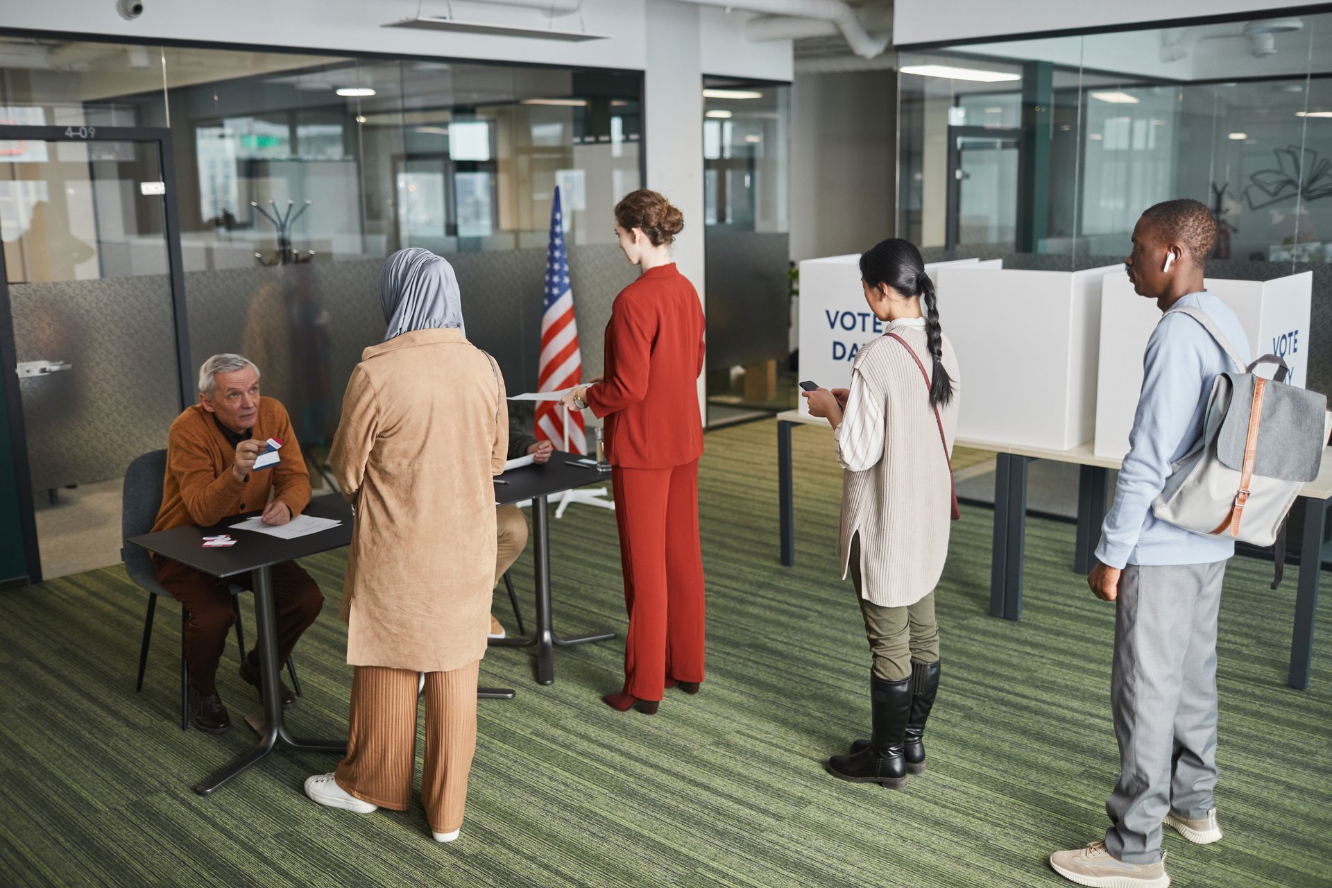 Voters queue at a polling station with ballot boxes visible