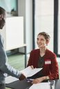 Woman in Orange Blazer Smiling Handing a Month a Document