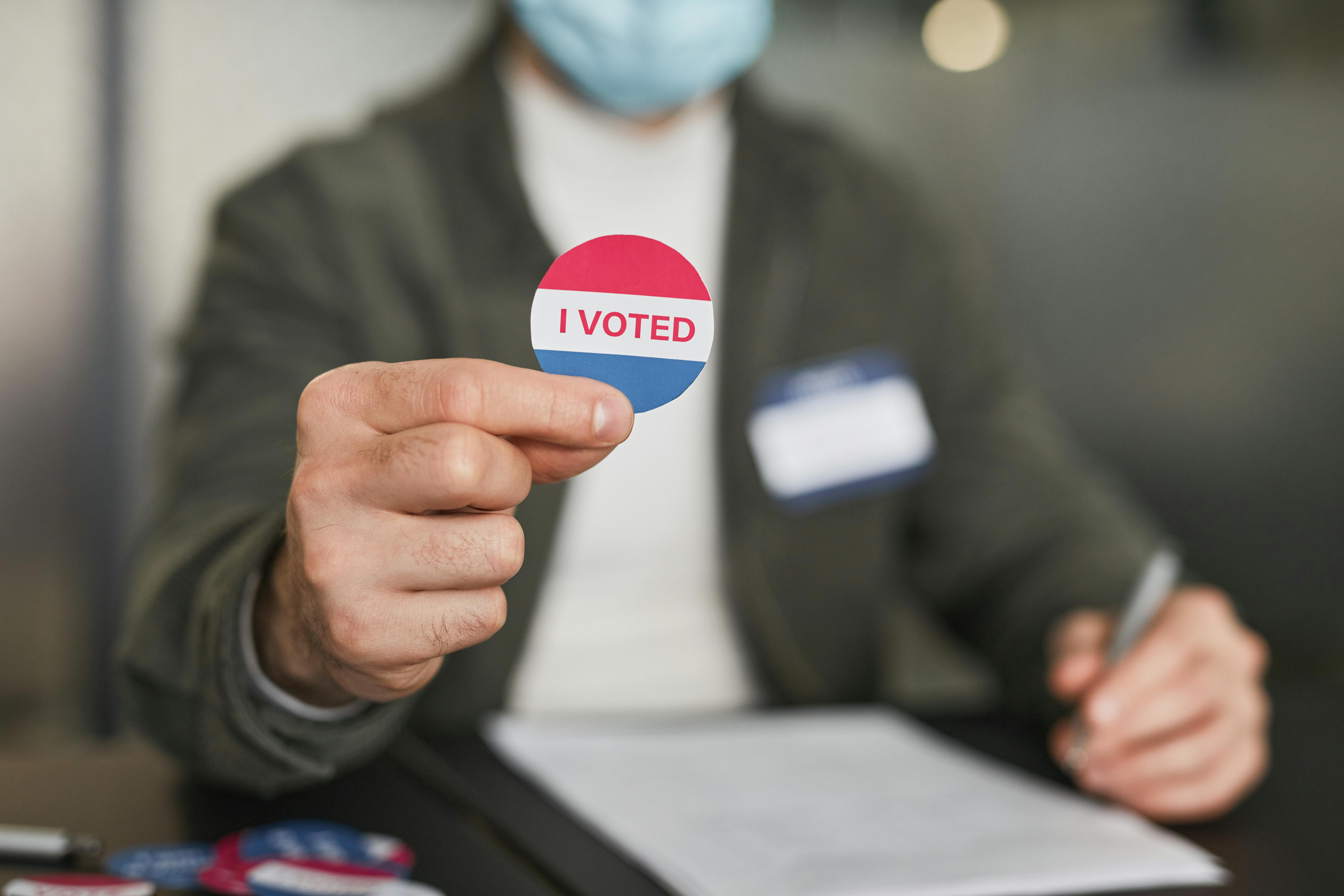 a person holding a badge with i voted