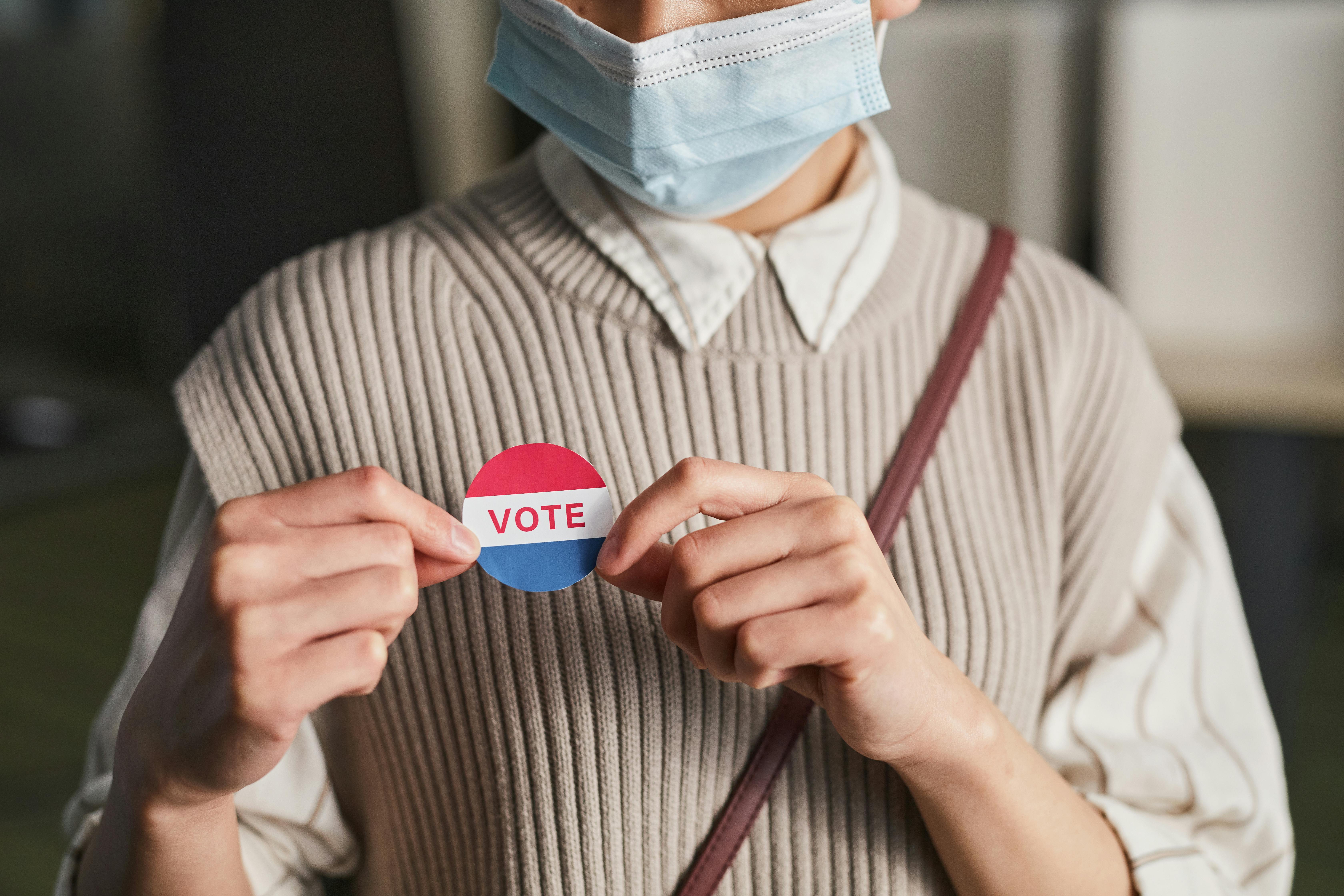 a person holding a vote badge