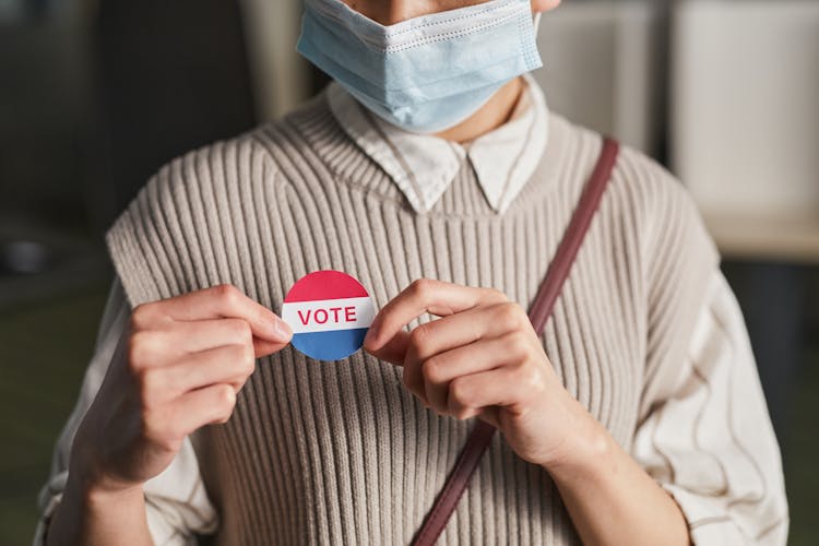 A Person Holding A Vote Badge