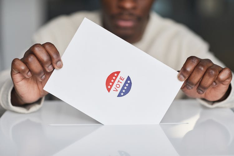 Person Putting A Paper In White Ballot Box