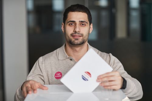 Free A man with a 'I am a voter' sticker casting his ballot on election day. Stock Photo