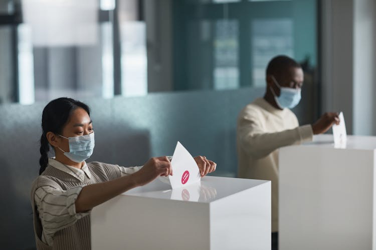 People Casting Their Voting Ballots In A Box