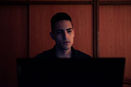 A young man working on his laptop, focused and serious, in an indoor setting with warm lighting — photo by Nicolás Langellotti on Pexels