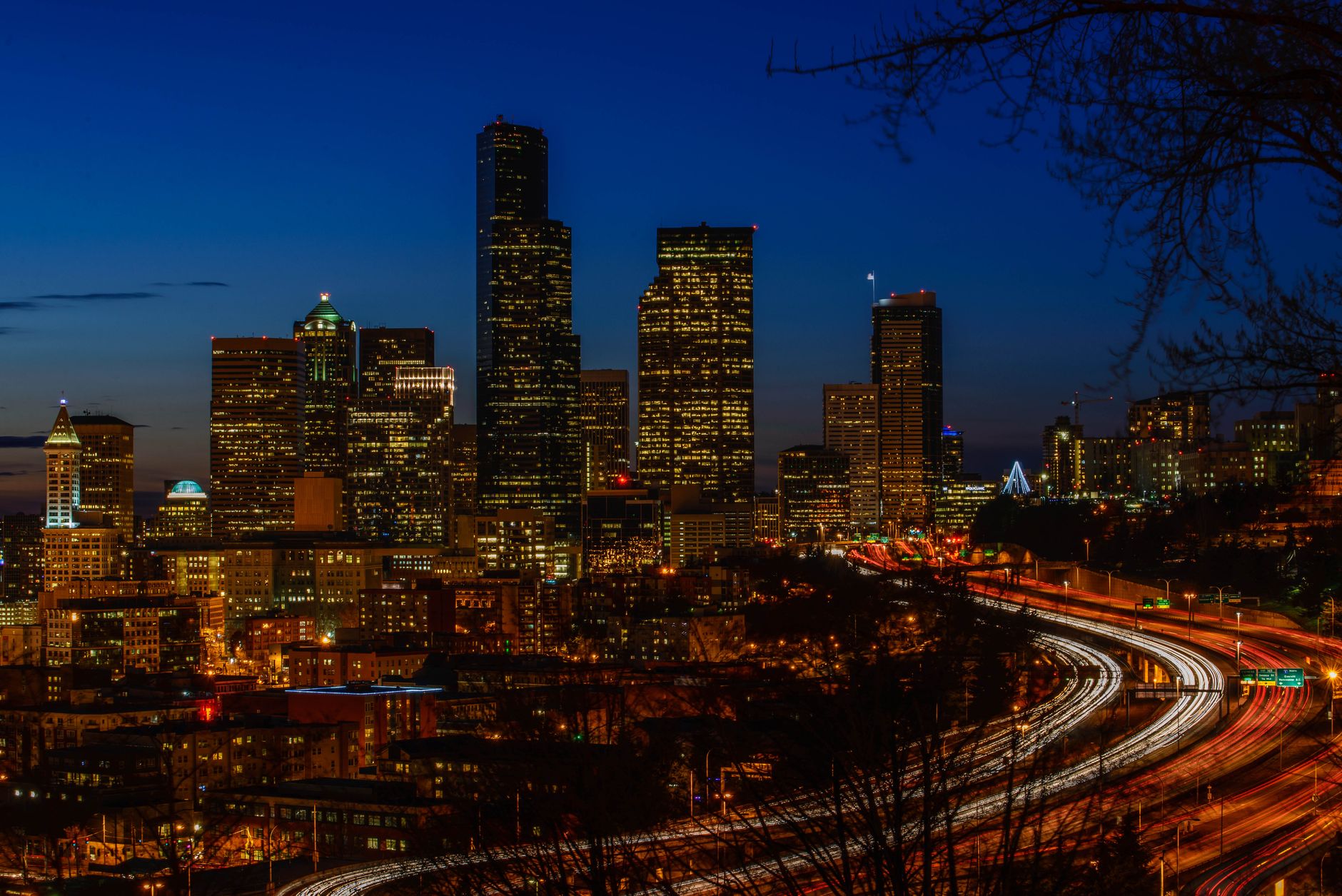 A vibrant night view of Seattle's illuminated skyline showcasing urban skyscrapers and light trails.