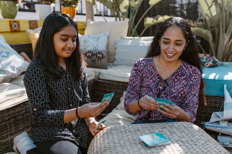 Mother And Daughter Playing Card Game On The Table