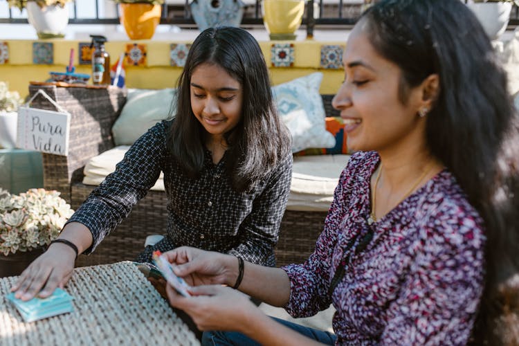 Mother And Daughter Playing Card Game On The Table