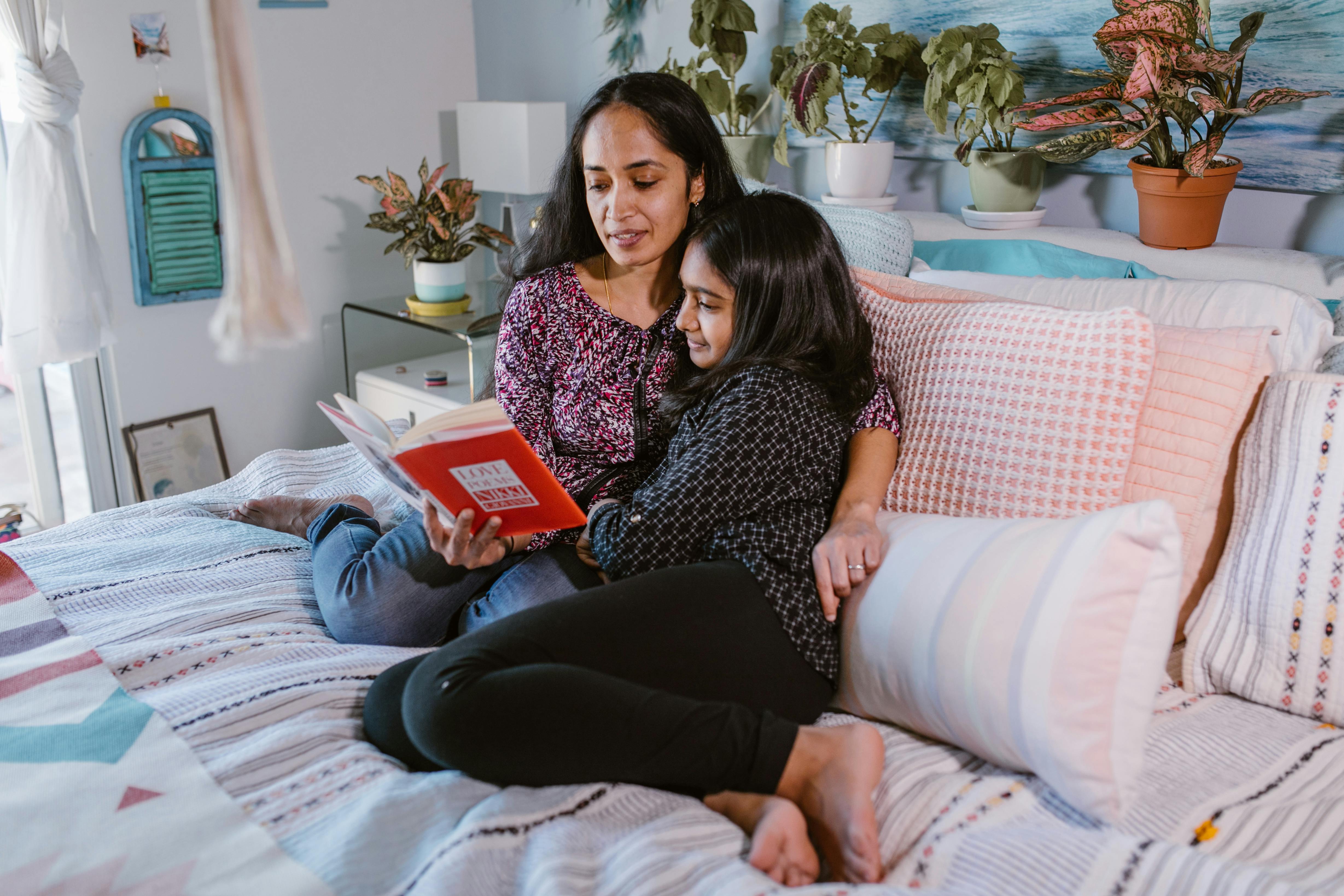 a woman reading a book together with her daughter