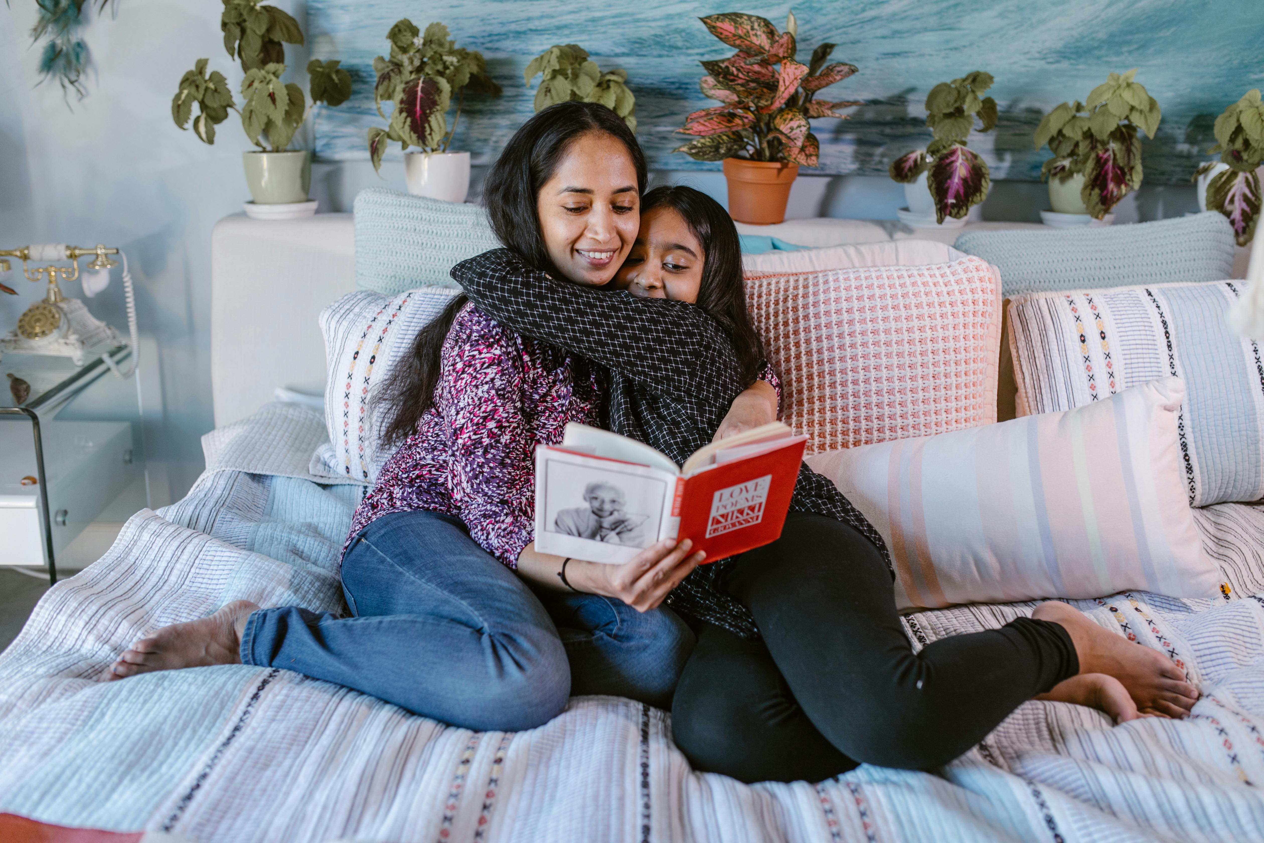 a young girl embracing a woman while reading a book together