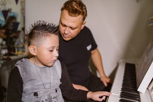Man in Black Crew Neck Shirt Playing Piano with His Son