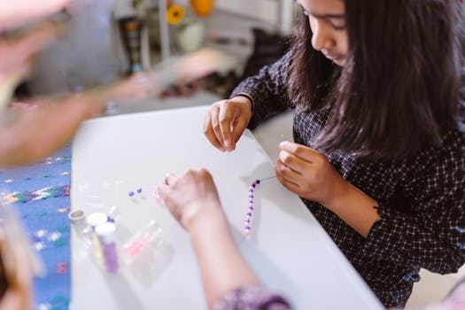 A child creating bead bracelets creatively indoors, focused on art and craft activity.