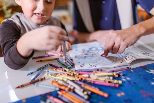 A child and adult share a creative coloring session with crayons on a table.