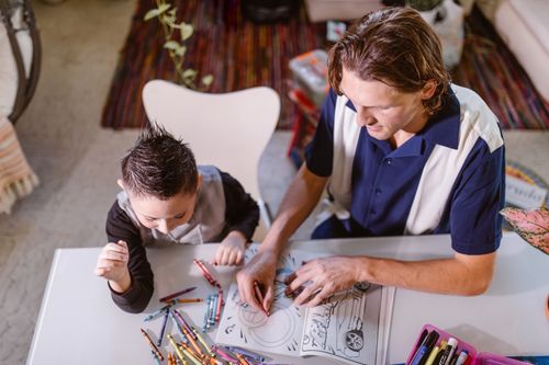 Free A father and son enjoy coloring together, fostering creativity and bonding in a cozy indoor setting. Stock Photo