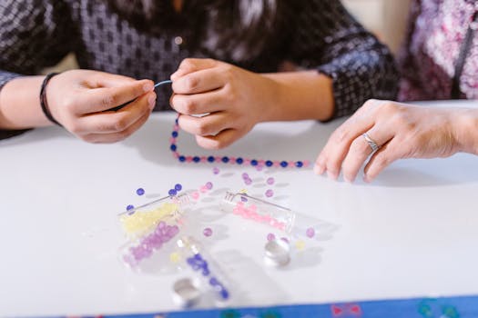 Child learning fine motor skills through bead crafting with parental guidance.