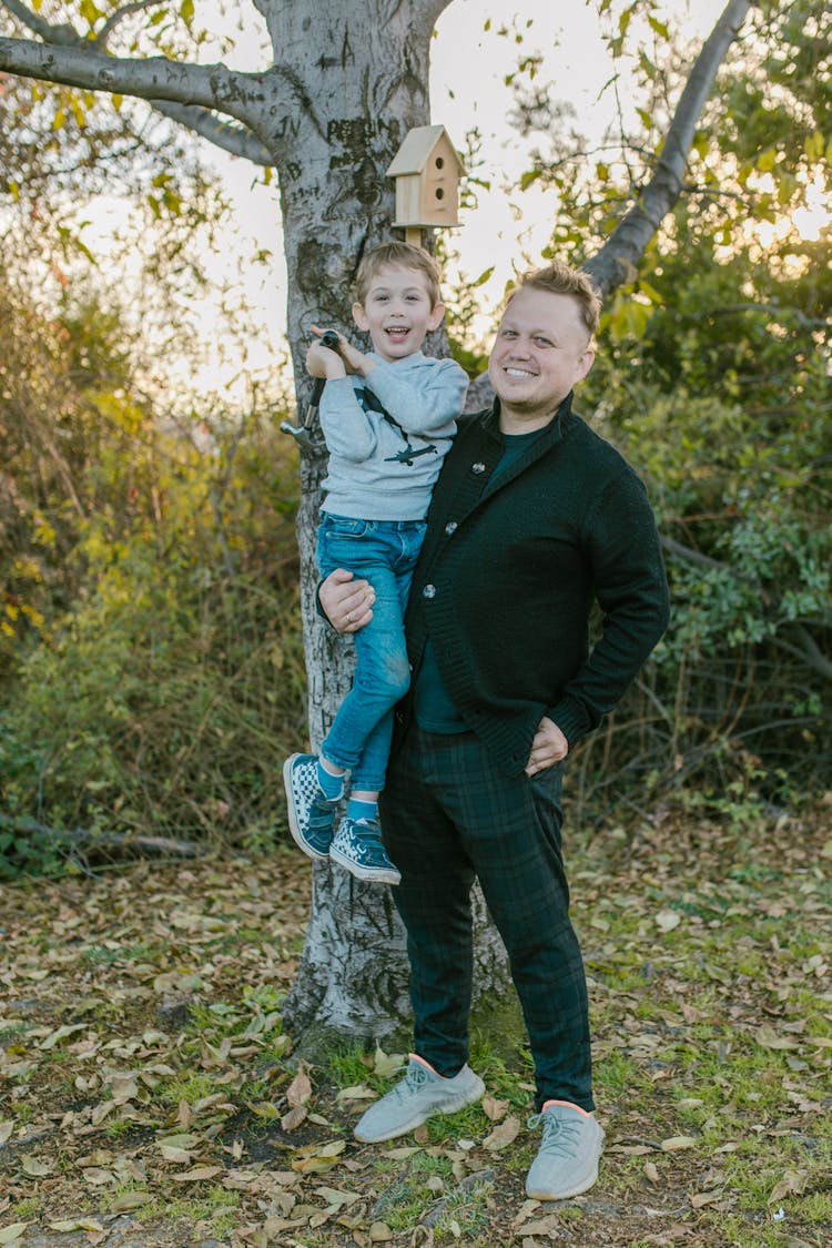 Man Carrying A Boy Beside A Tree 