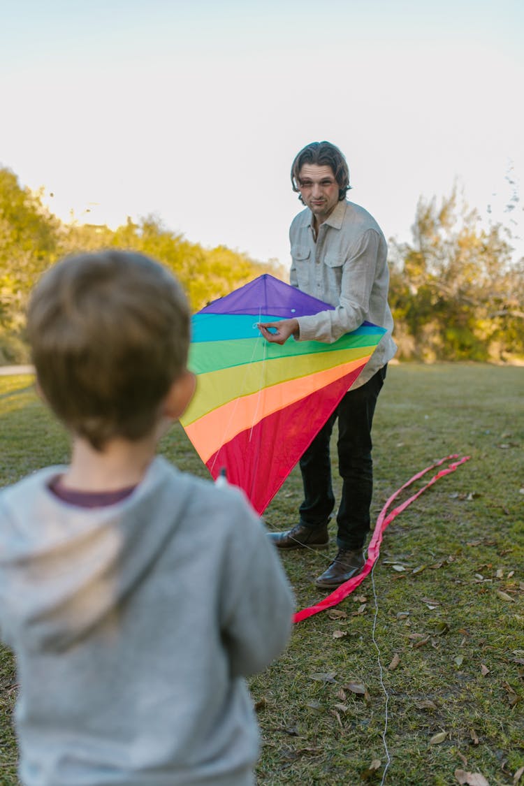 Father And Son Flying Kite On The Field