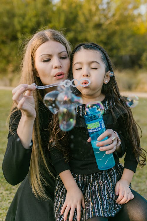 Free A Girl in Black Dress Blowing Bubbles Stock Photo
