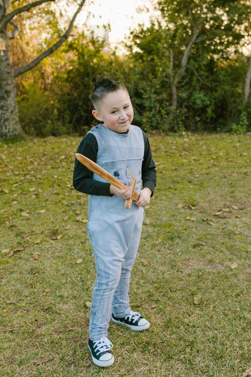 Young Boy in Denim Overall Holding a Wooden Sword