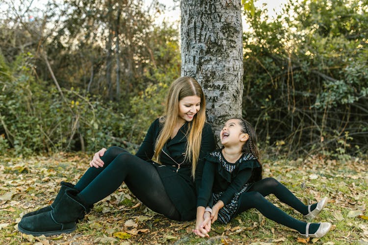 Woman And Her Child Sitting On The Ground Under The Tree