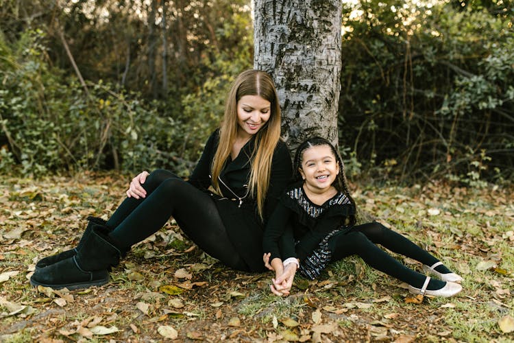 Woman And Her Child Sitting On The Ground Under The Tree