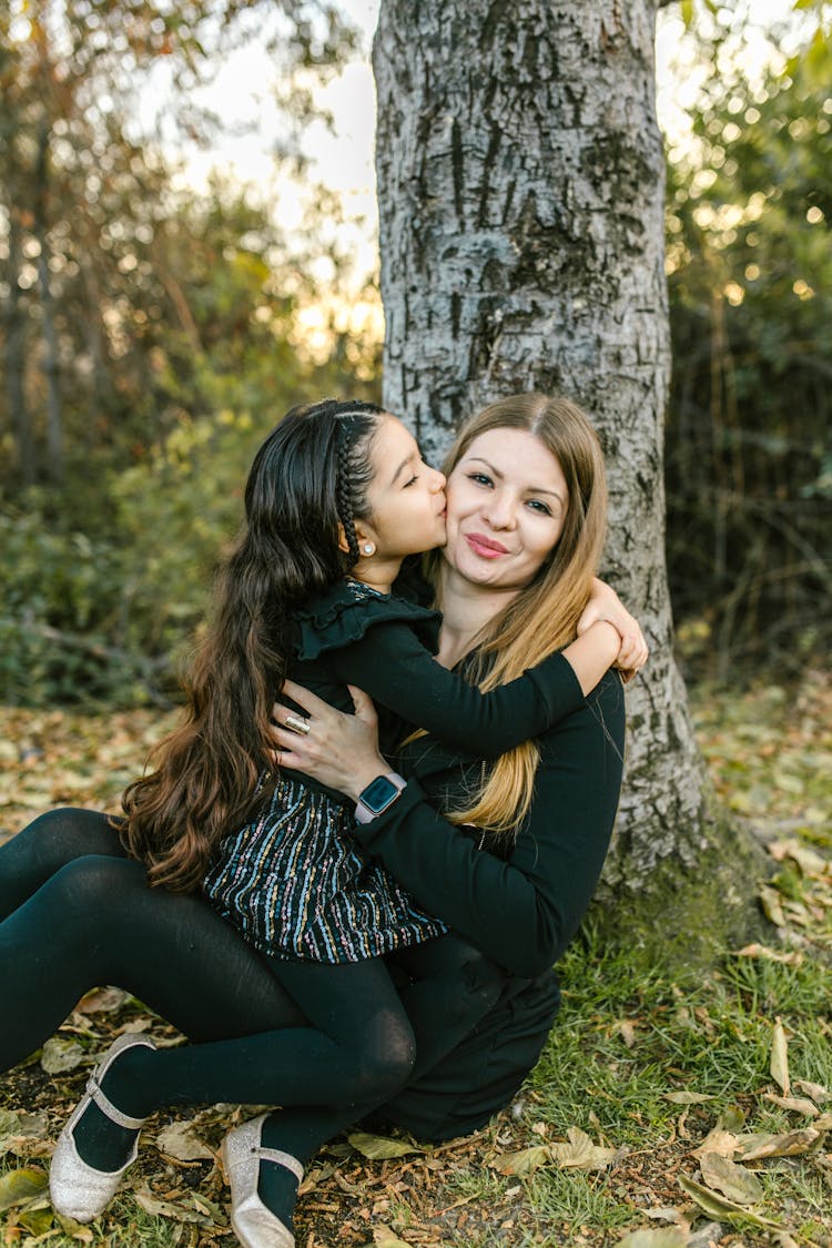 Woman And Her Child Sitting On The Ground Under The Tree