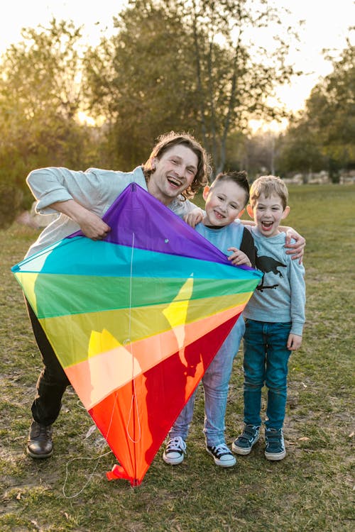 Free A Happy Man Holding a Kite with Two Kids Stock Photo