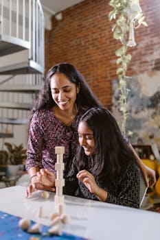 Mother and daughter enjoying building wooden blocks at home, fostering creativity and bonding.