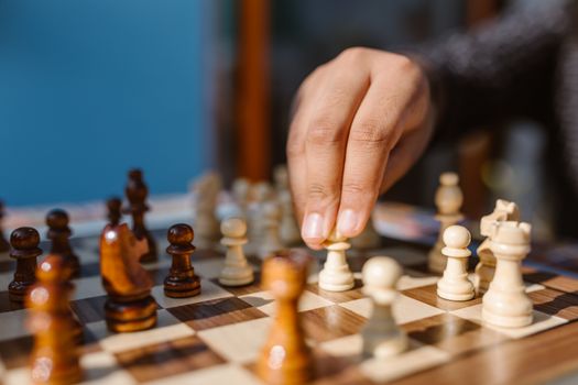 A hand moves a piece on a chessboard in an intense game moment.