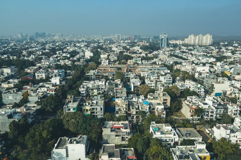Aerial shot of Gurugram's urban landscape capturing dense residential buildings and city skyline.