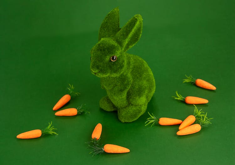 Green Rabbit Plush Toy And Carrots On Green Surface