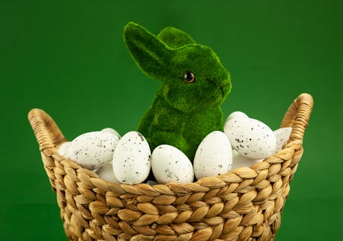 Close-up of a Green Bunny Figurine and White Eggs in a Woven Basket