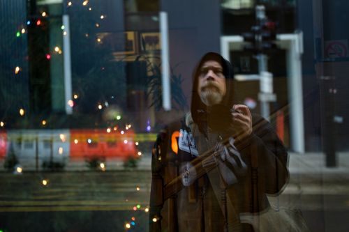 Free Through glass of serious middle aged bearded male traveler taking selfie on photo camera standing in front of showcase in city Stock Photo