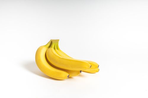 Free A fresh bunch of ripe yellow bananas displayed on a clean white surface, perfect for food presentations or healthy lifestyle themes. Stock Photo