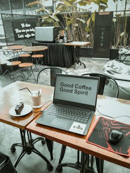 Inviting cafe workspace featuring a laptop with 'Good Coffee Good Spirit' text, coffee, and cake.