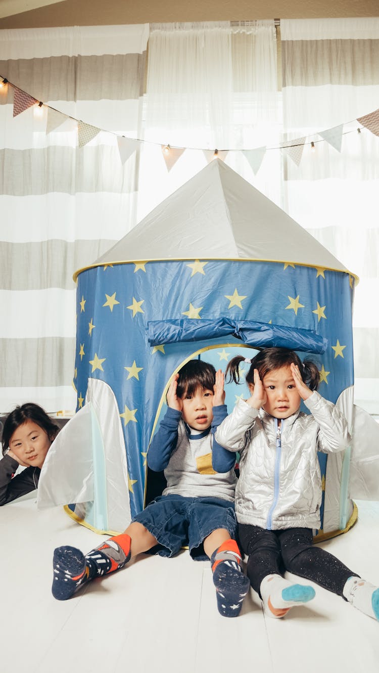 Children Sitting Near A Tent With Hands On Head