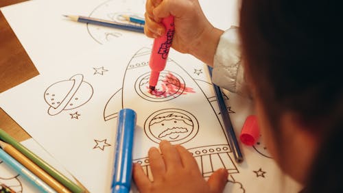 Child Holding a Colored Marker on Paper