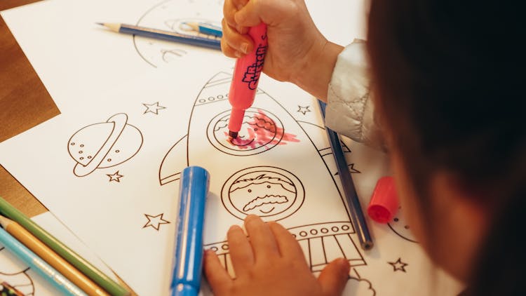 Child Holding A Colored Marker On Paper