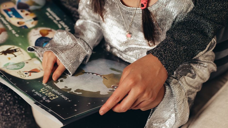 A child reads a colorful storybook with an adult's guidance, learning and bonding.