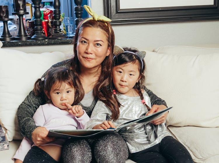 Woman Holding A Book With Her Daughters