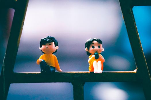 Cute small colorful miniatures of boy and girl placed on shabby metal structure on street against blurred background in city