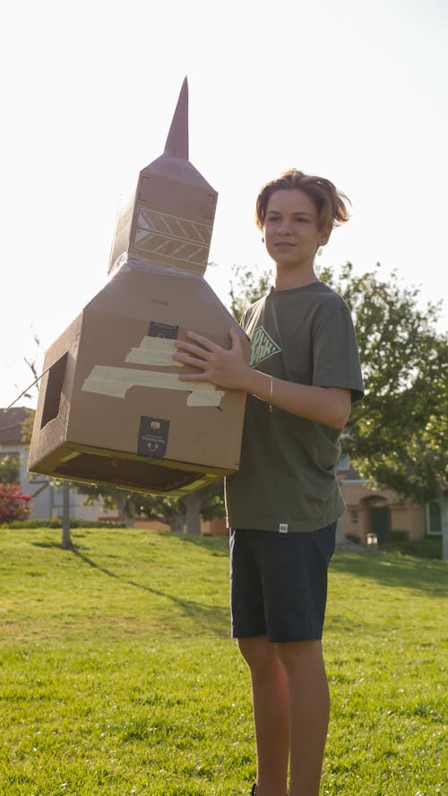A Boy Holding a Cardboard Rocket