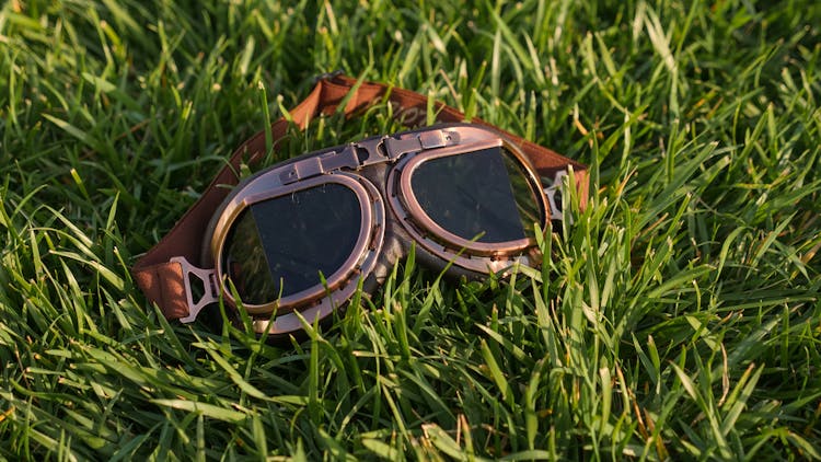 Brown Aviation Goggles On Green Grass