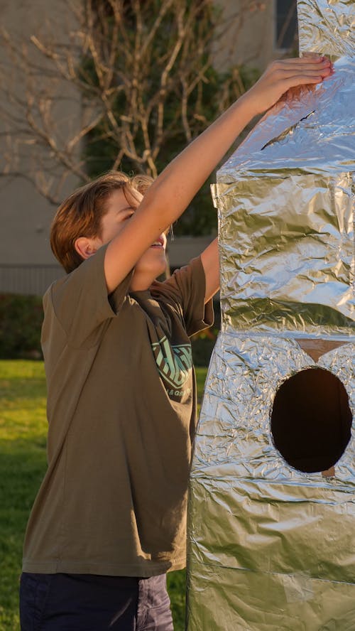 A Boy in Olive Shirt Standing beside a Rocket