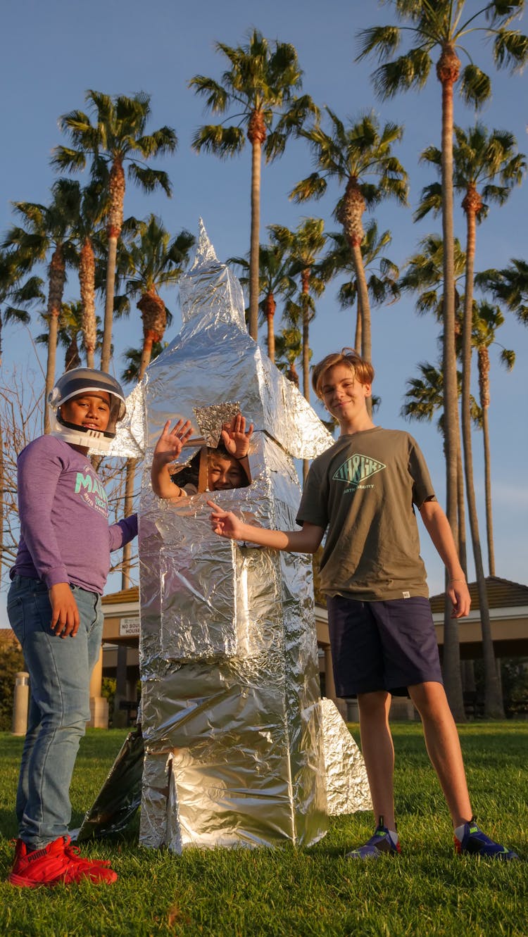 Boys Standing Beside A Cardboard Rocket