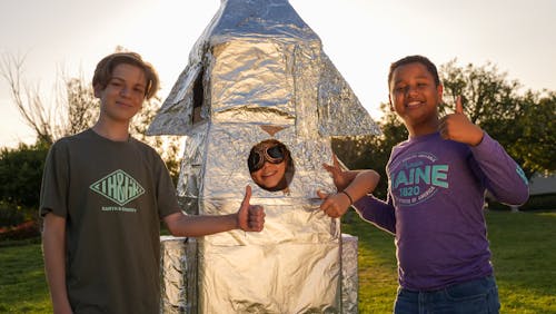 Interracial Boys Giving a Thumbs Up with A Wrinkled Silver Object 