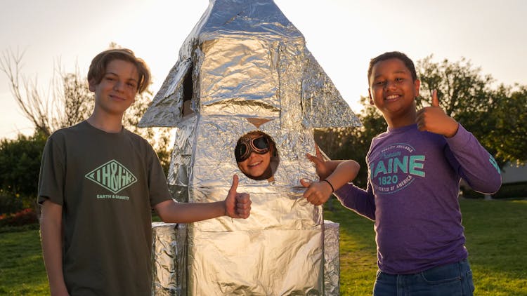 Interracial Boys Giving A Thumbs Up With A Wrinkled Silver Object 