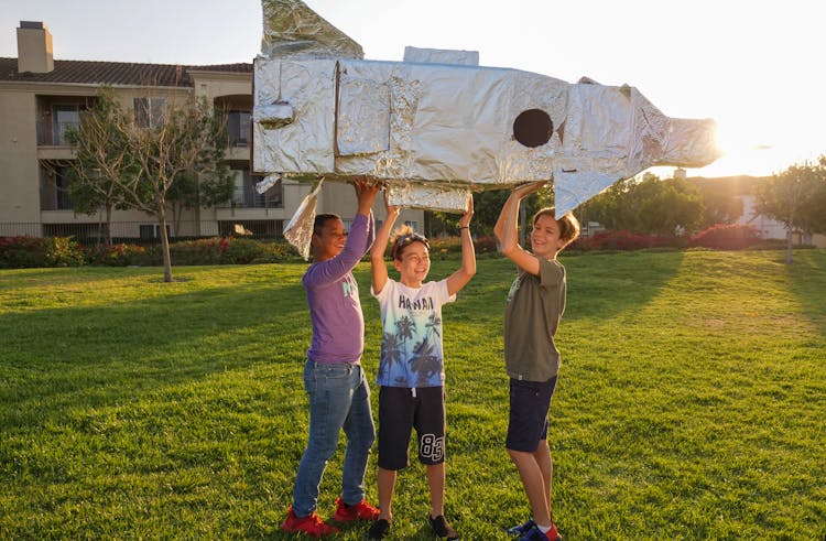 Boys Playing A Cardboard Rocket