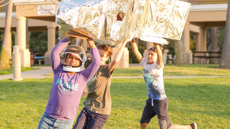 Boys Playing A Cardboard Rocket